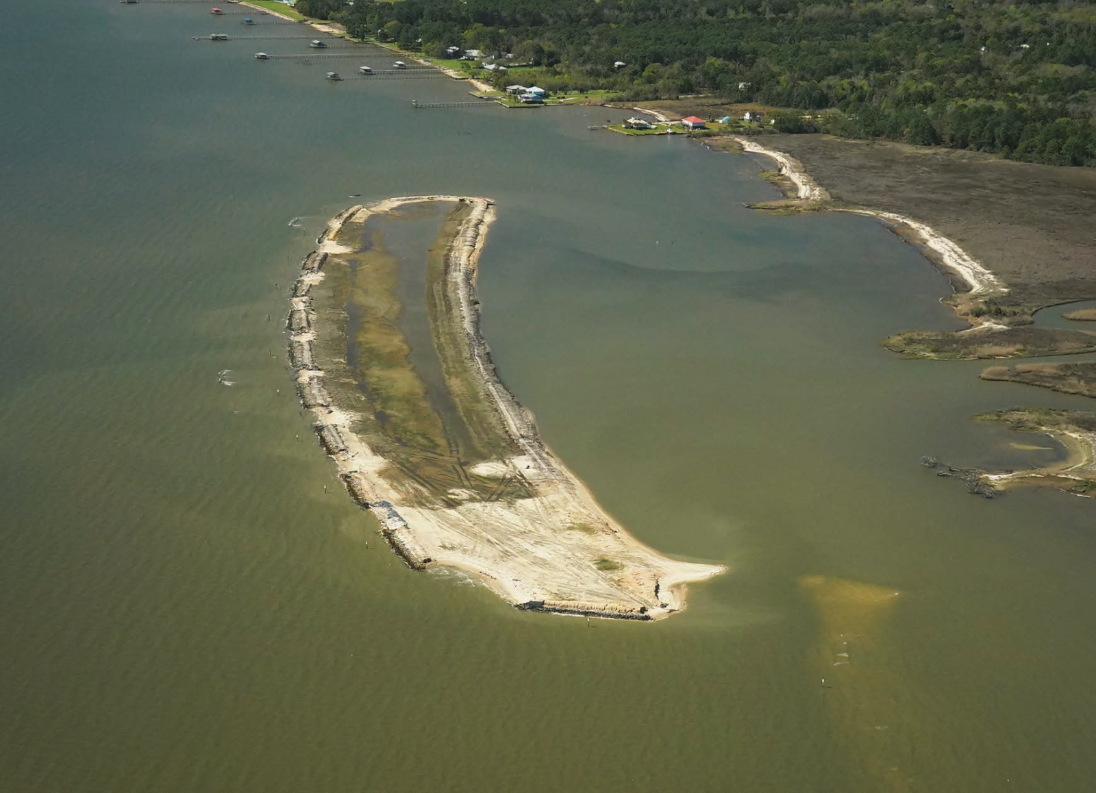 Aerial view of the Deer River marsh and shoreline restoration project showing a curved dredged material island in open water.