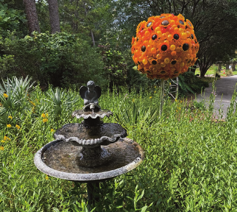 Decorative orange sphere sculpture in the garden with a fountain nearby