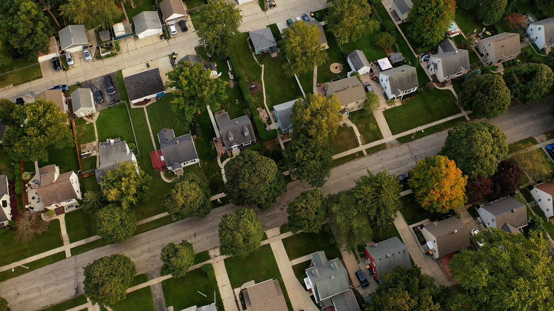 Aerial drone view of American suburban neighborhood at daytime. Establishing shot of America's suburb. Residential single family houses pattern, trees, street