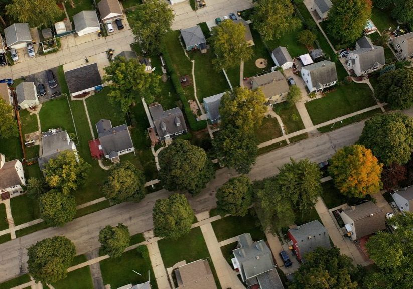 Aerial drone view of American suburban neighborhood at daytime. Establishing shot of America's suburb. Residential single family houses pattern, trees, street