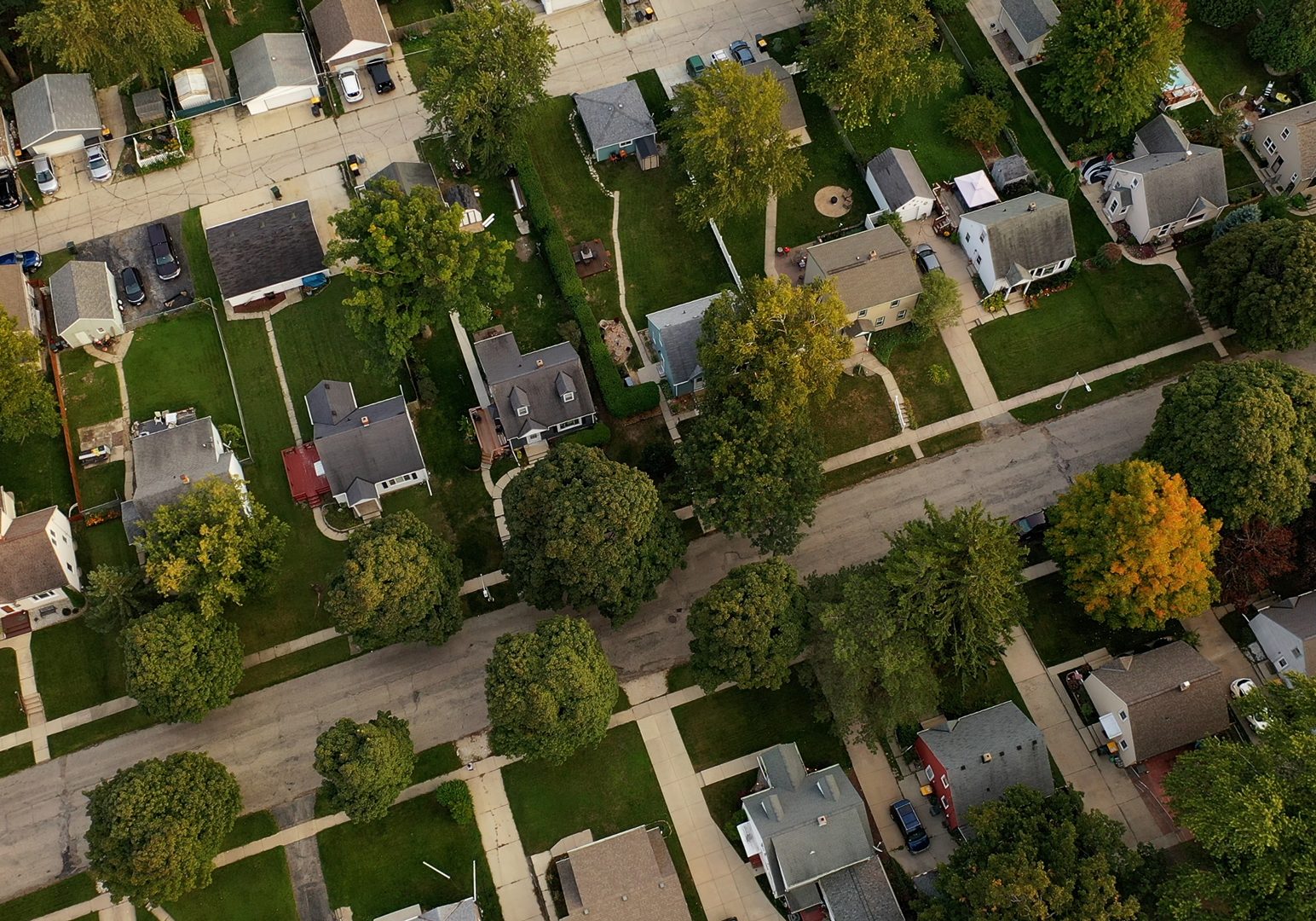 Aerial drone view of American suburban neighborhood at daytime. Establishing shot of America's suburb. Residential single family houses pattern, trees, street