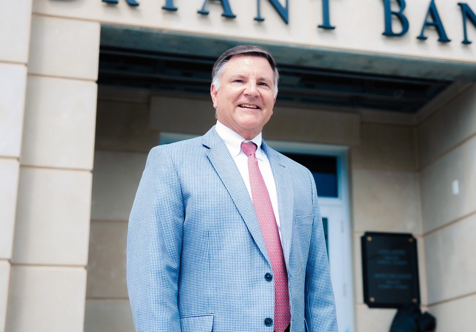 Michael Holland, Market President for Mobile, Bryant Bank, standing in front of Bryant Bank signage