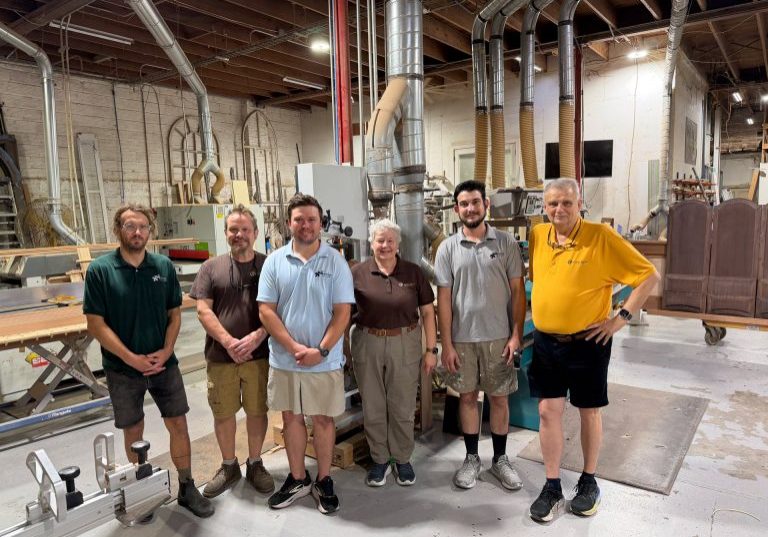 Six people standing together in the Oakleigh Custom Woodworks workshop