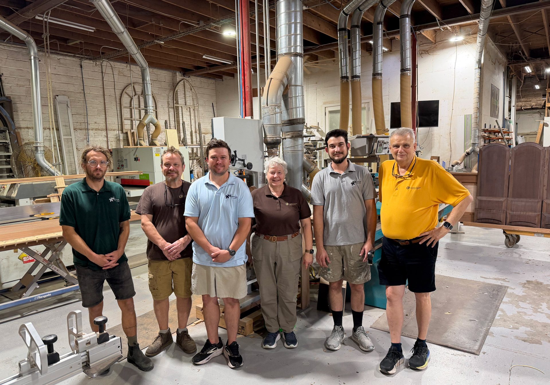 Six people standing together in the Oakleigh Custom Woodworks workshop