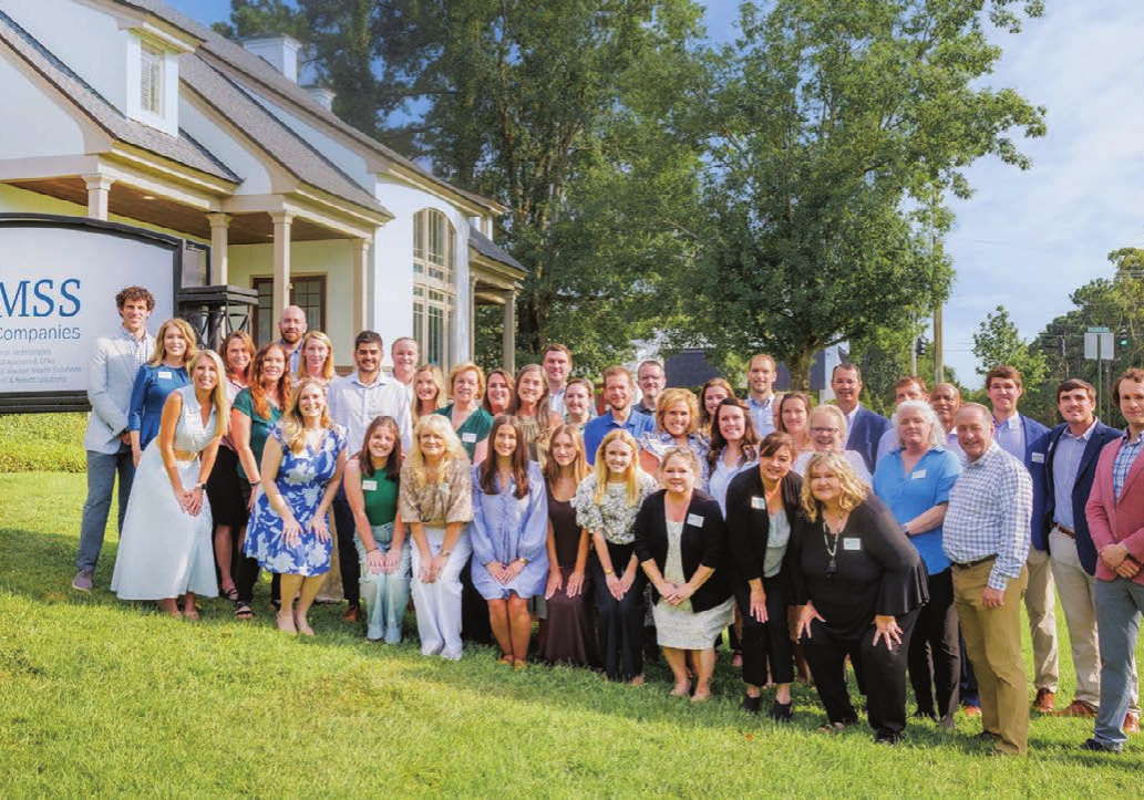 Group photo of newly combined Avizo and BMSS team members in front of BMSS Family of Companies signage